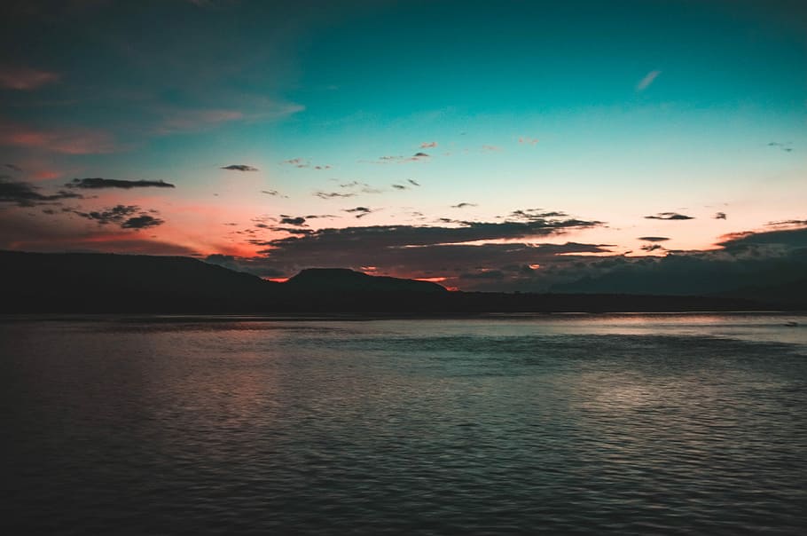 sea near mountain silhouette during blue hour, body of water near mountain HD wallpaper