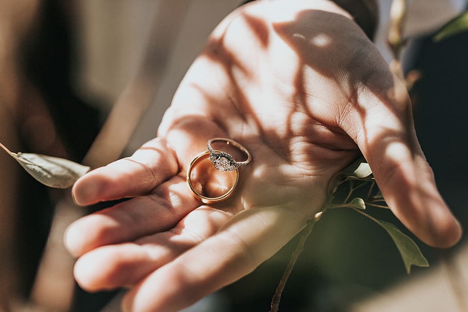 person holding bridal ring set, two gold-colored rings on left hand HD wallpaper