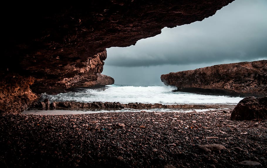 shore under rock formation during cloudy day, cliff near sea under cloudy sky during daytime photo HD wallpaper
