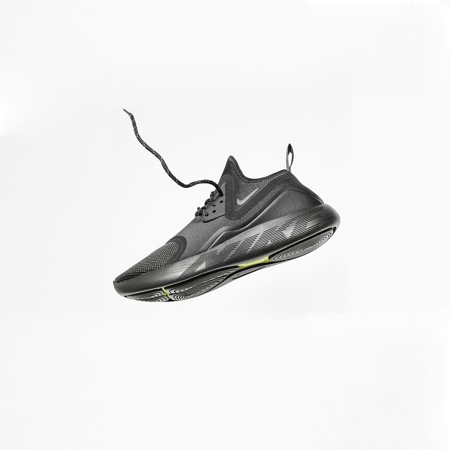 unpaired gray Nike running shoe, black Nike basketball shoe, sneaker