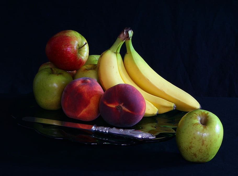 fruits on top of a black table, apples, bananas, peaches, platter