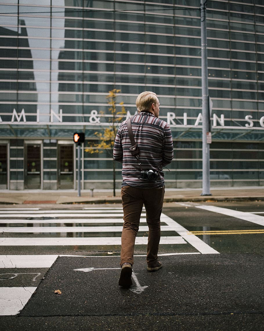 man's gray and black stripe long sleeve and brown shorts walking on street pedestrian, man walking on road beside building, HD wallpaper