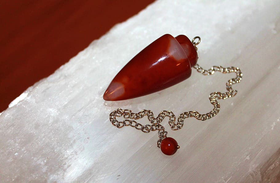 red stone fragment pendant with gold-colored necklace, arrowhead