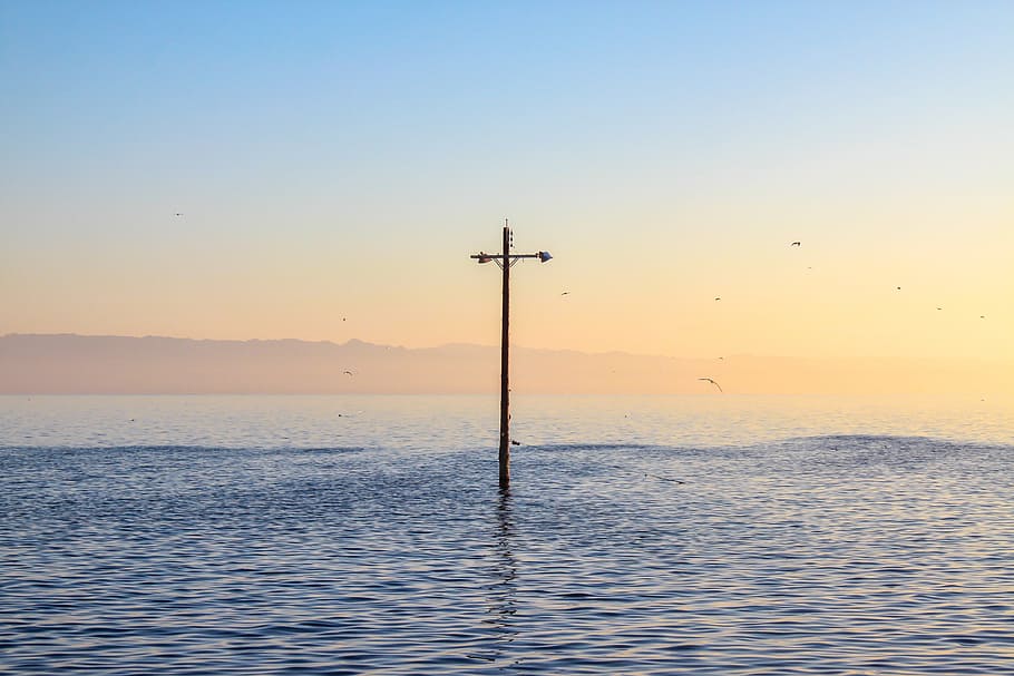brown standing post in body of water under blue sky during golden hour HD wallpaper
