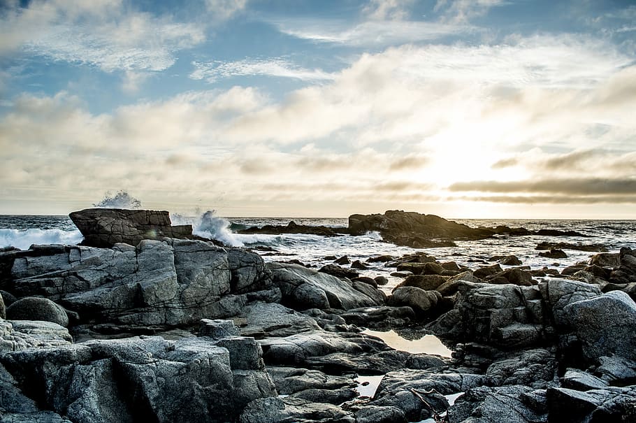 gray concrete rocks on body of water under blue and white cloudy sky, gray rocks near seashore HD wallpaper