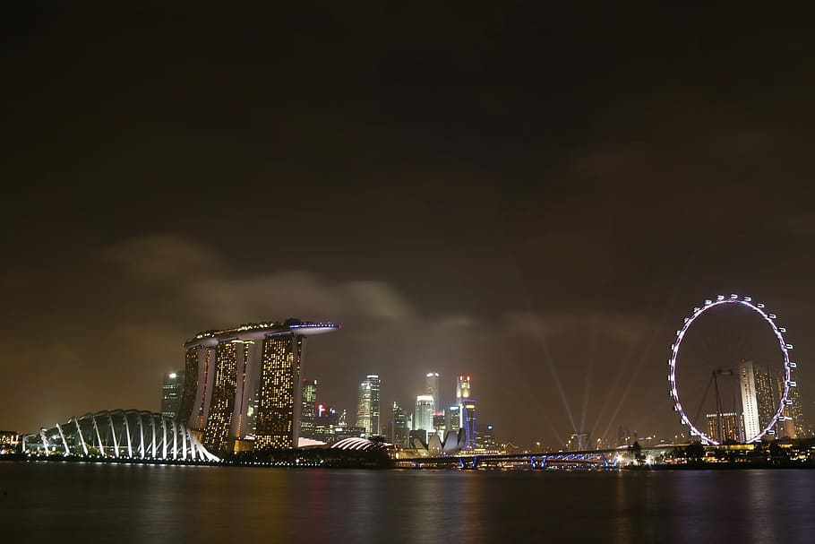 lighted ferris wheel near body of water and city buildings during night time HD wallpaper