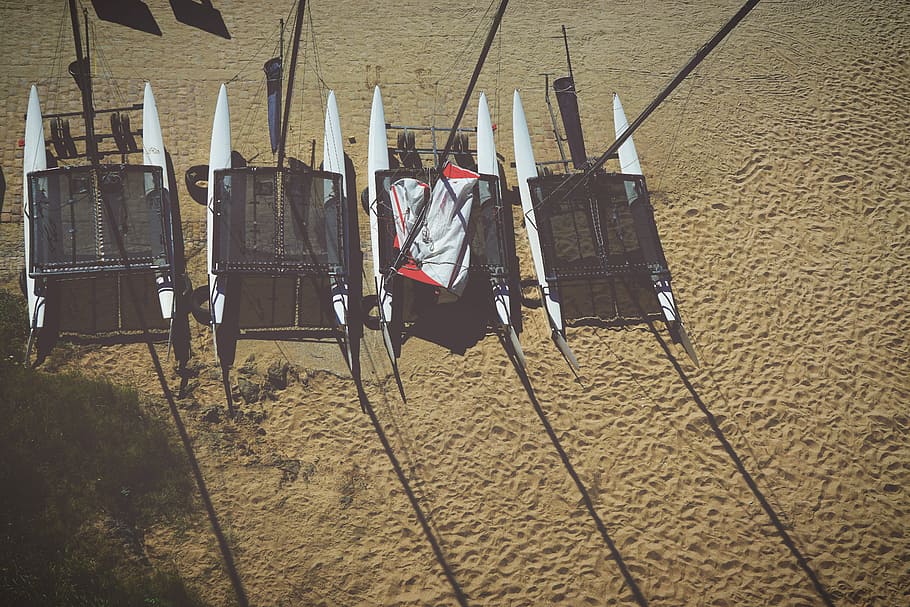 four white pontoon boats on beige sand, white and black sail boat on beach HD wallpaper