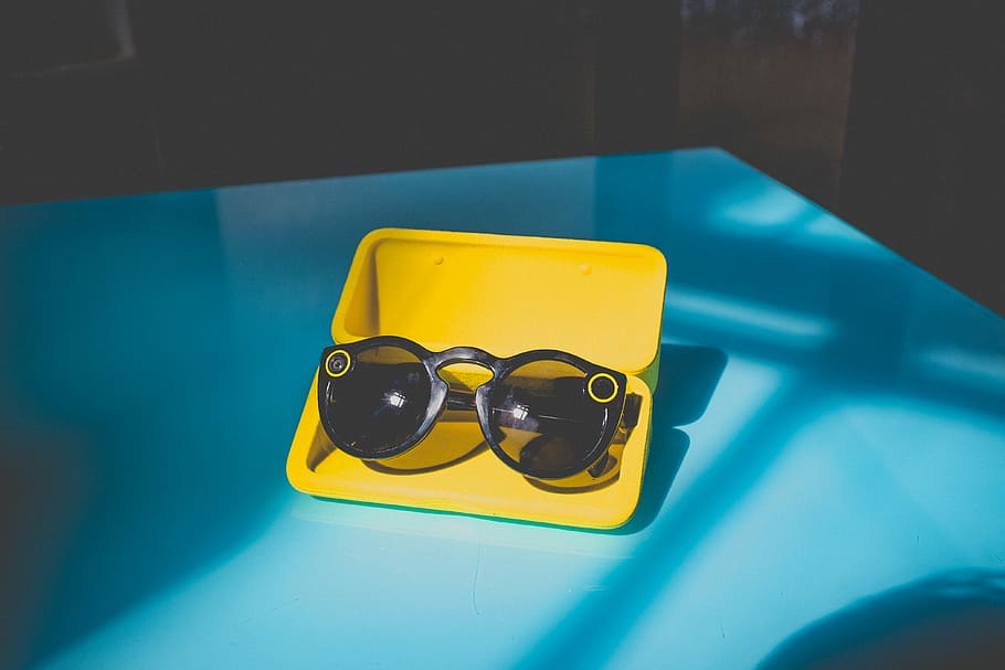 black sunglasses in yellow case on table, black sunglasses on yellow case