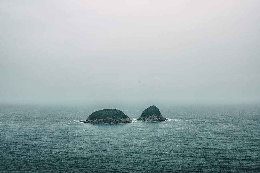 two gray rock formations on the middle of sea at daytime, two islands in the middle of ocean HD wallpaper