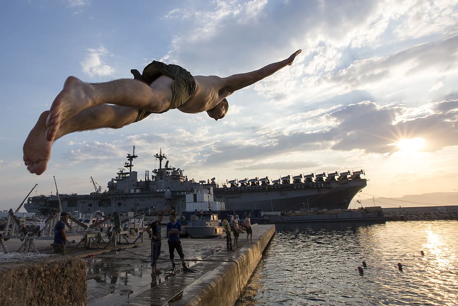man wearing brown bottoms diving on body of water during daytime HD wallpaper
