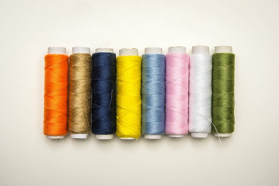 eight thread rolls on white platform, sewing, failure, workbasket