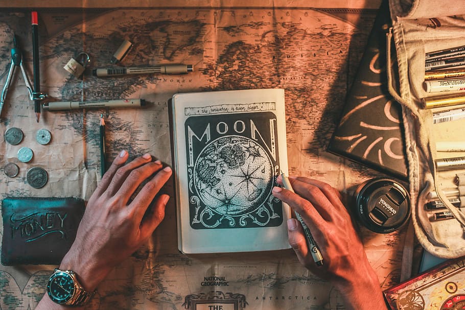 Moon book on top of world map, person holding pen with Moon notebook HD wallpaper