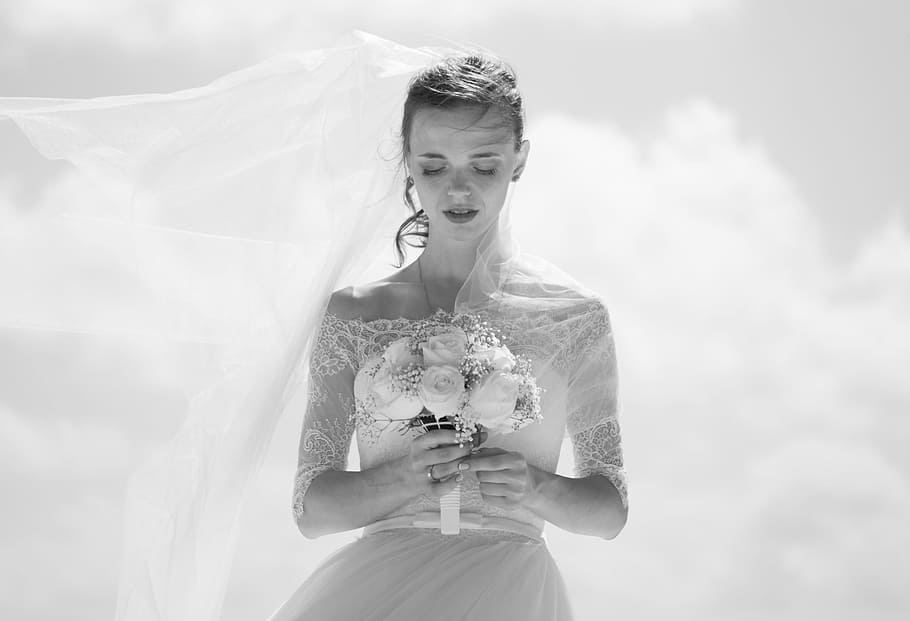 grayscale picture of bride holding flower bouquet, grayscale photo of woman holding flowers
