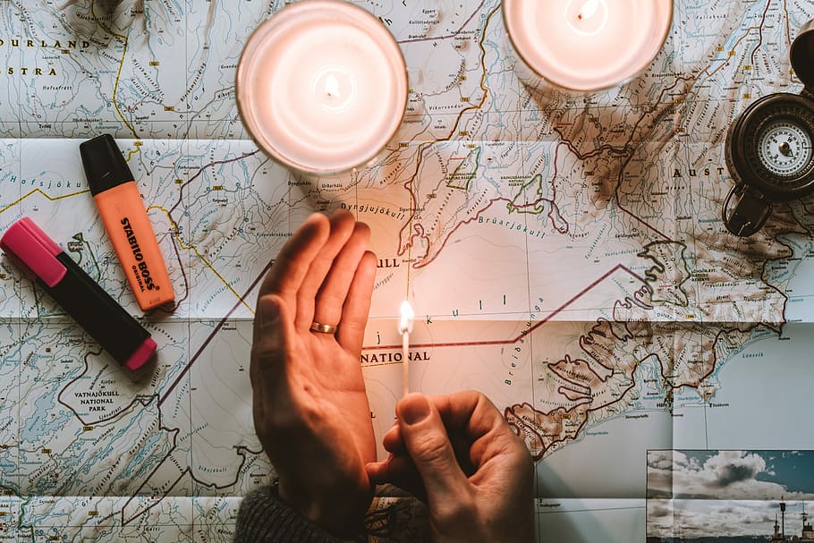person lighting match on top of map, person holding lighted matches stick on top of navigational charting map HD wallpaper