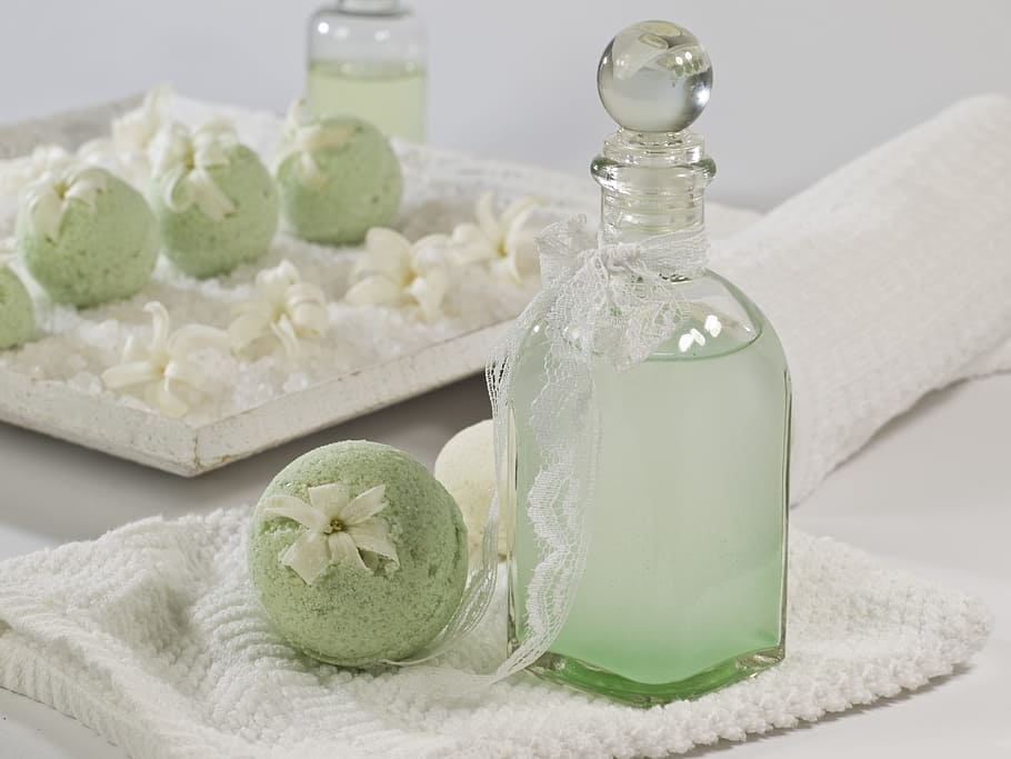 clear glass bottle beside green cake pops placed on white knitted textile