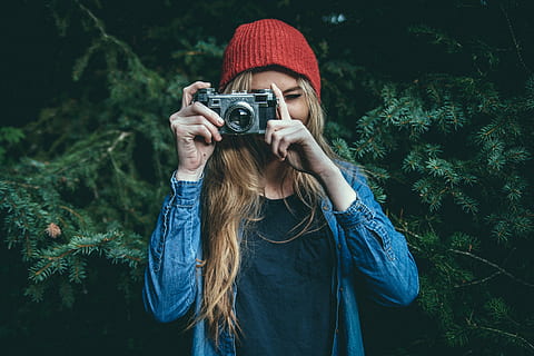 selective focus photography of woman wearing blue denim jacket holding gray film camera taking picture HD wallpaper
