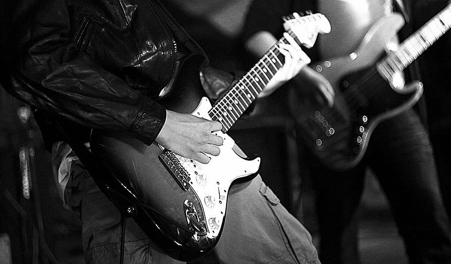 grayscale photo of two men playing electric guitars, concert