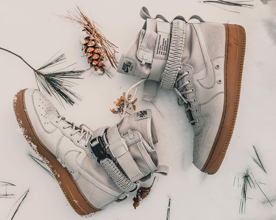 pair of gray Nike high-top sneakers on snow, pair of white-and-brown Nike Air Force 1 shoes