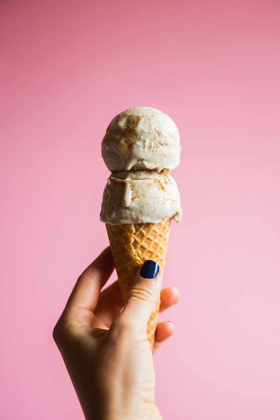 person holding ice cream on cone, person holding ice cream with cone