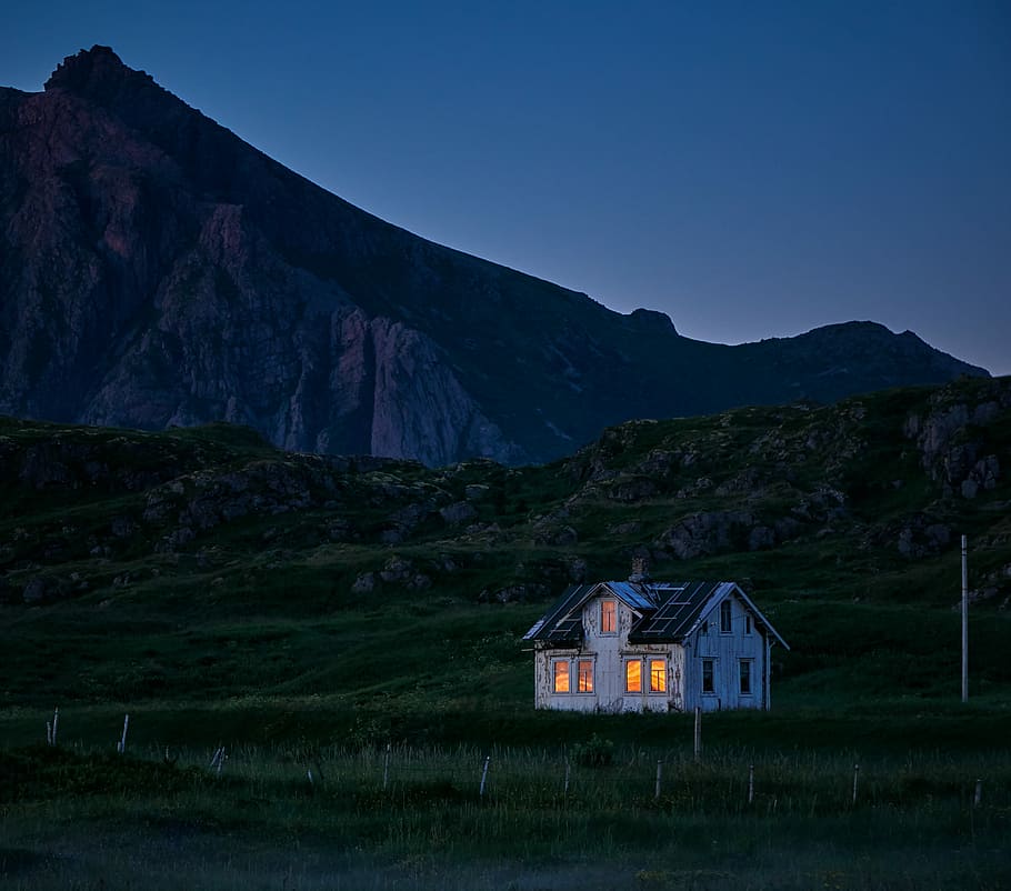 lighted house on green field, white and black house and mountain at night time