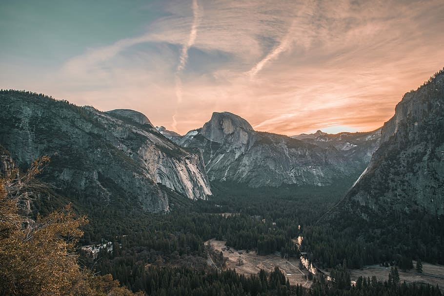 mountains surrounded by trees during golden hour, sunlight behind mountains HD wallpaper