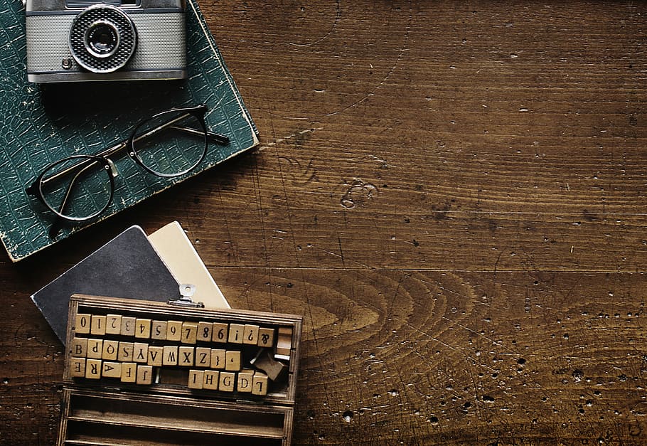 still life photography of gray camera, black framed eyeglasses and brown letter chips HD wallpaper