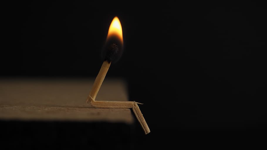 Lighted Matchstick on Brown Wooden Surface, black background