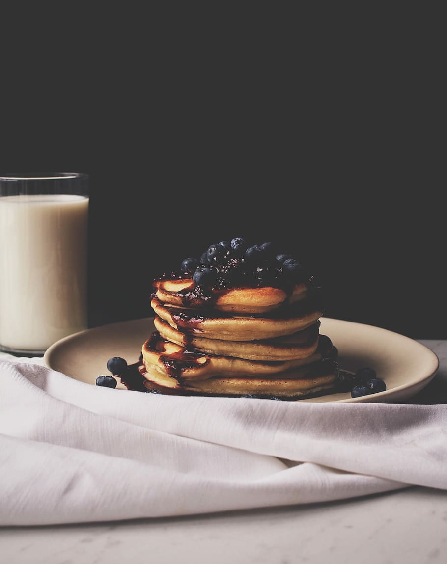 food photography of pancake top with blueberries on white ceramic plate beside a glass of milk HD wallpaper
