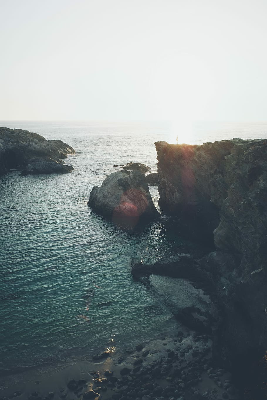 cliff near seashore at daytime, aerial photography of mountain on body of water HD wallpaper