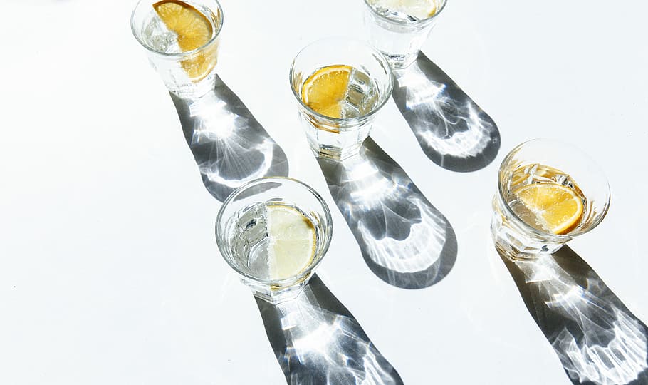 five clear shot glasses, five clear glasses on white surface