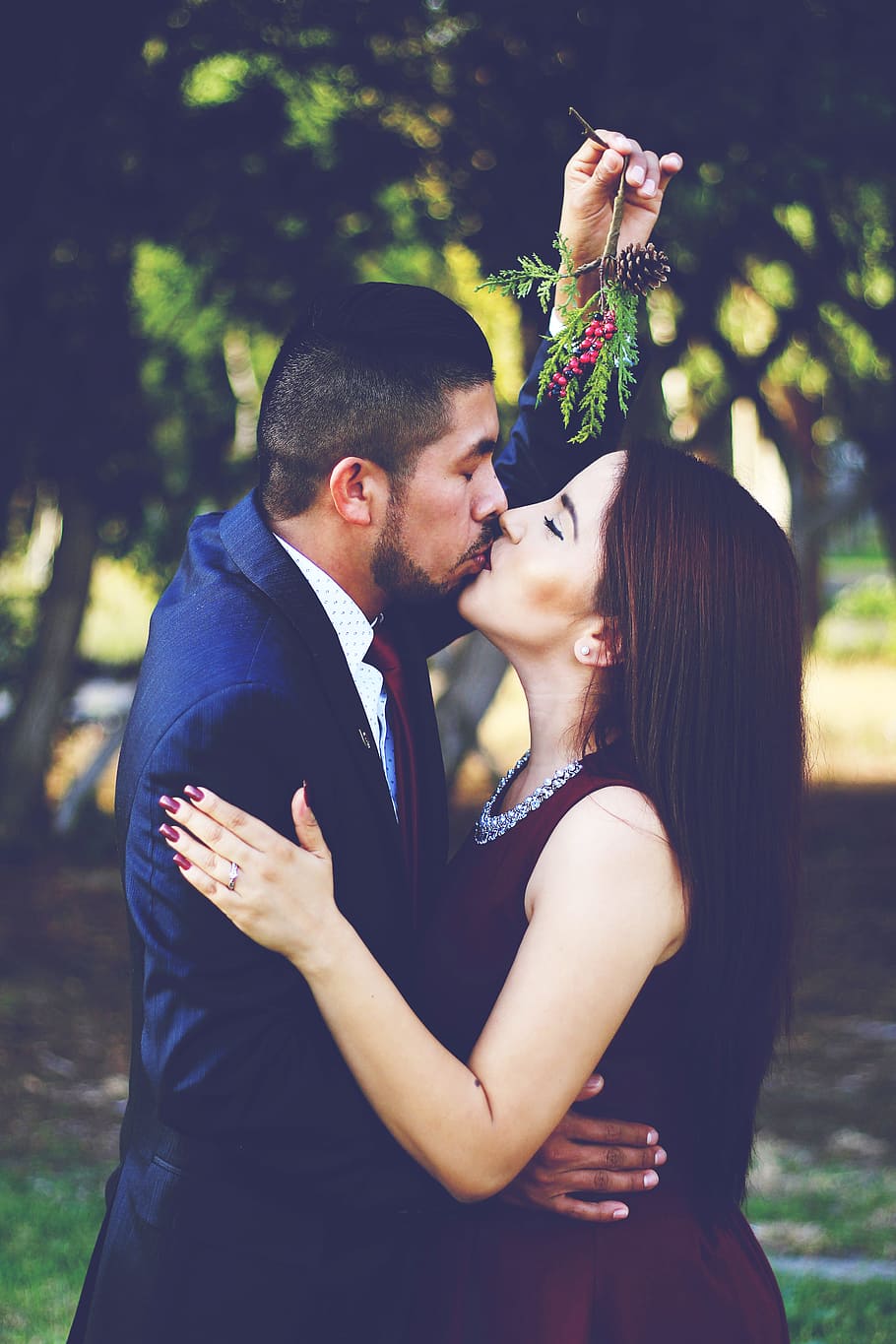 man and woman kissing near trees, couple kissing under mistletoe