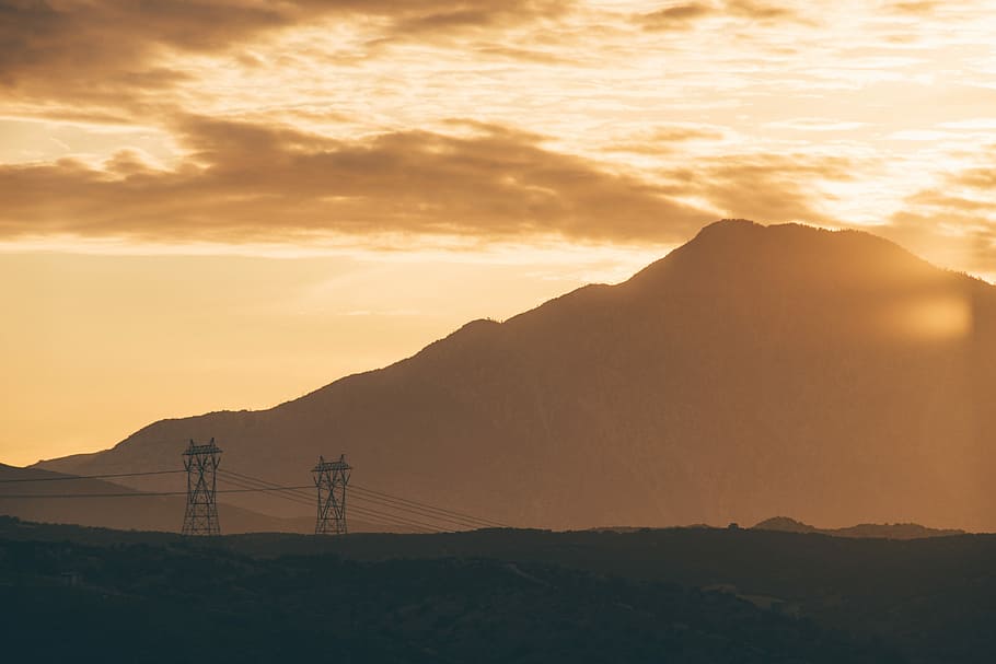 sun shining over mountain and two transmission towers, silhouette of mountain and utilitypoles during orange sunset HD wallpaper