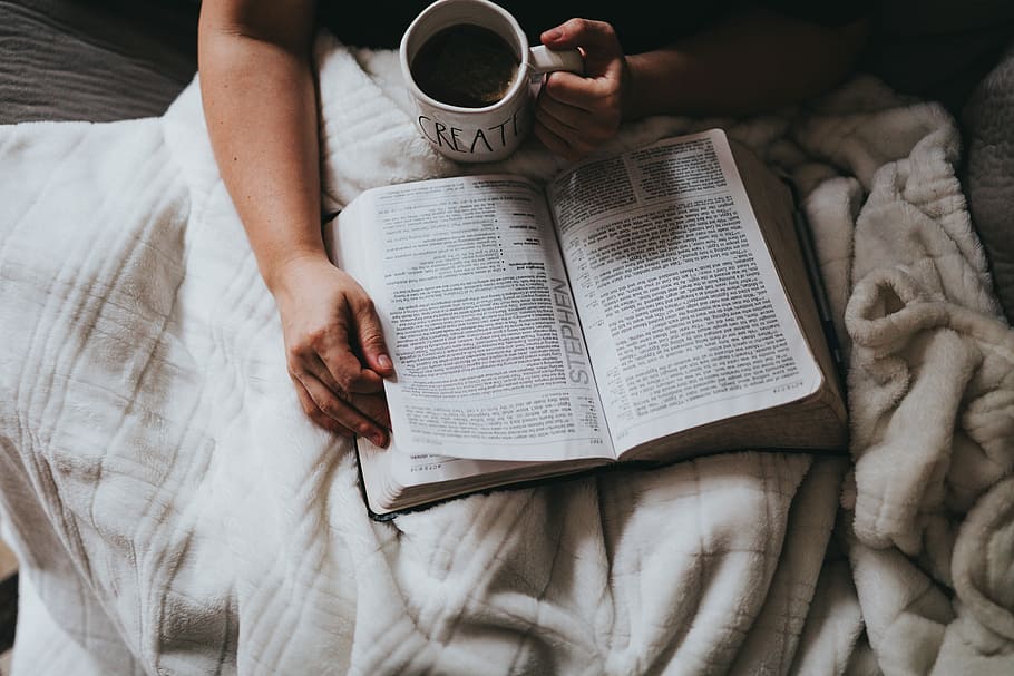 person holding cup while reading book, person holding mug and book laying on gray surface HD wallpaper