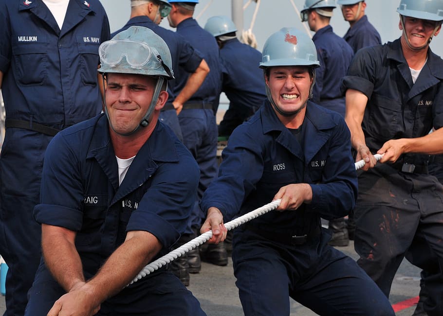 men wearing hard hats pulling rope near men, teamwork, sailors