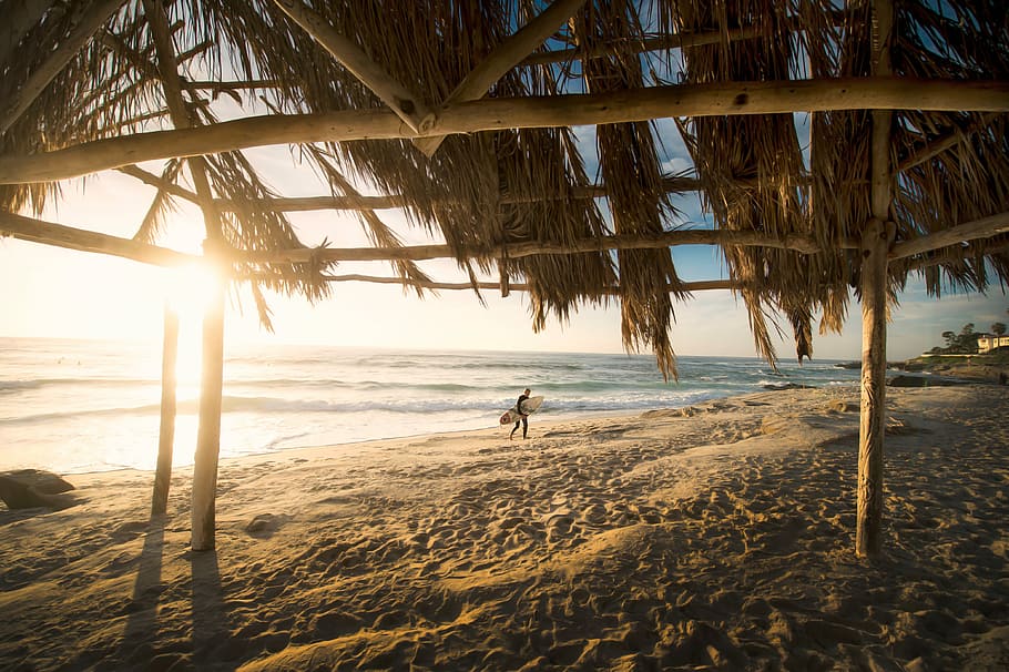person walking on beach during daytime, man holding surf board walking on beach during daytime HD wallpaper