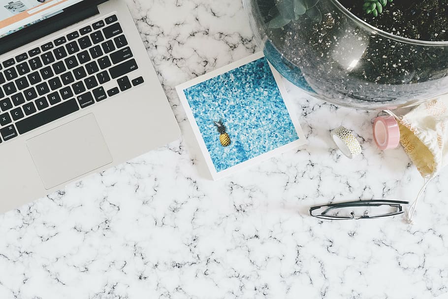 flat lay photography of MacBook beside pineapple card and black framed eyeglasses on black and white marble surface HD wallpaper