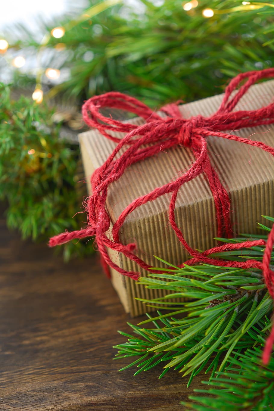 brown gift box with red ribbon wrap beside garland, christmas HD wallpaper