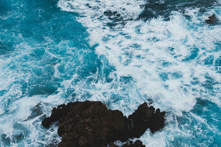 aerial photography of black rock formations near seawaves, ocean waves during daytime HD wallpaper
