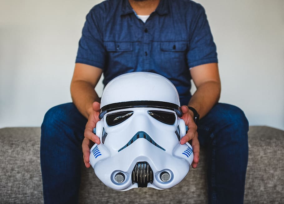 person sitting on sofa holding Stormtrooper helmet, man holding Star Wars Stromtrooper helmet HD wallpaper