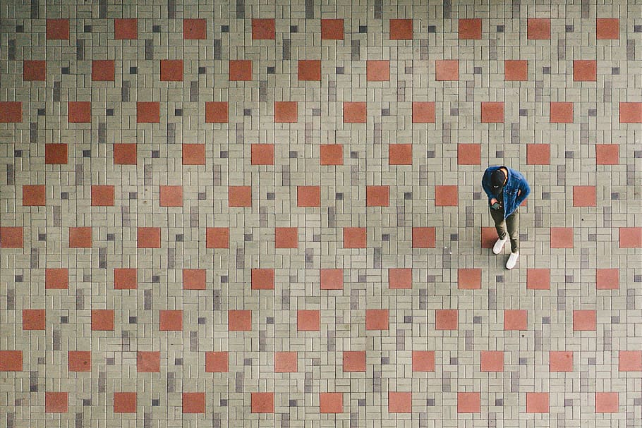 man standing on brown and beige ground, man wearing blue jacket holding smartphone HD wallpaper