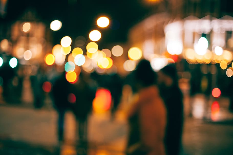 An out-of-focus look at people walking outside in a town at night with with blurs of dotted light all around, people on street with lights blurry photo