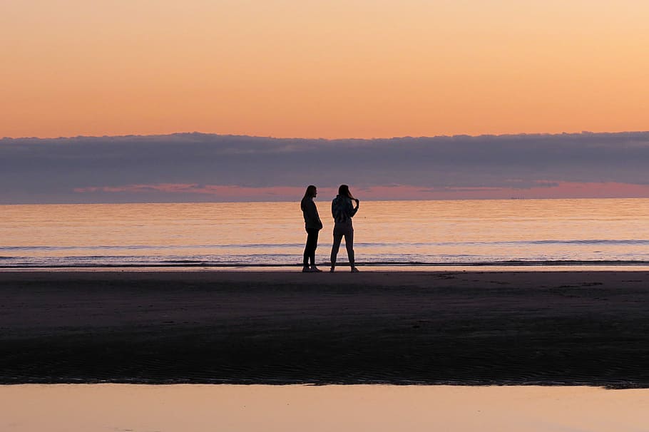 Friendship at sunset, man and woman silhouette stand on seashore HD wallpaper