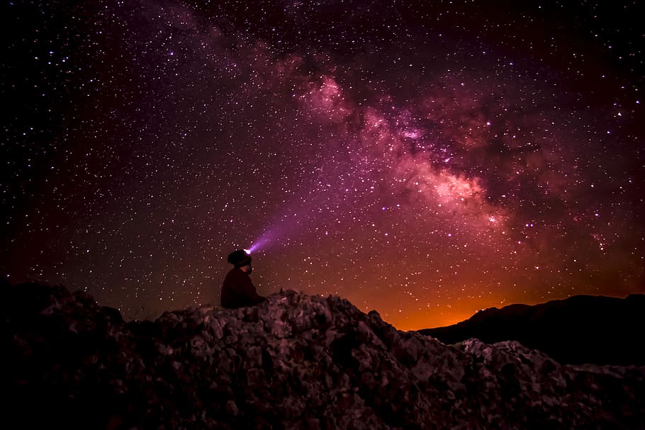 silhouette photo of person holding flashlight under milk way, person sitting in a rock hill with background of red cosmos in a sky HD wallpaper