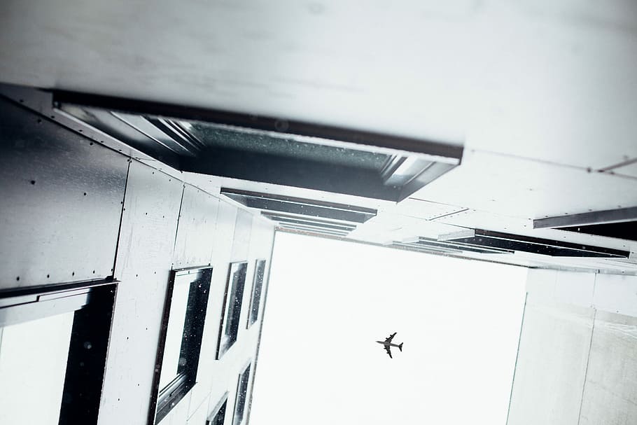 airplane above concrete building, worm's-eye view photography of building and airplane HD wallpaper