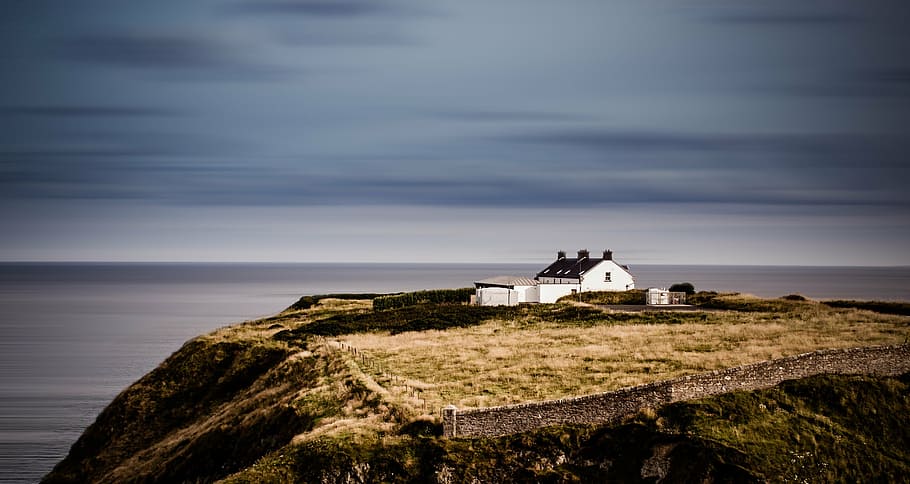 white concrete house on top of hill under gray sky at daytime HD wallpaper