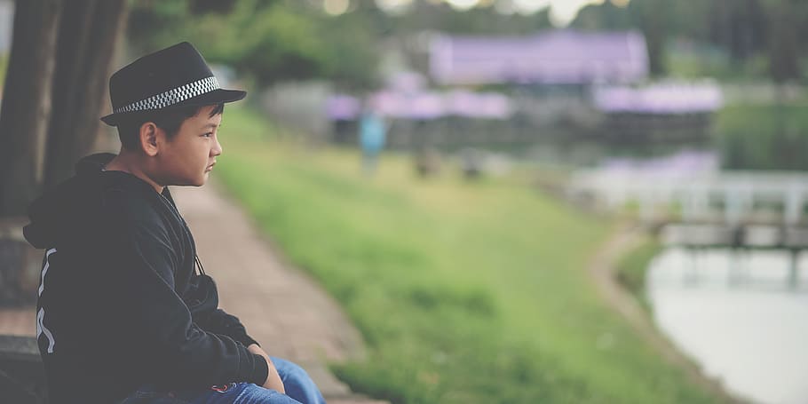 Boy in Black Jacket and Black Fedora Hat Sitting Near Body of Water HD wallpaper