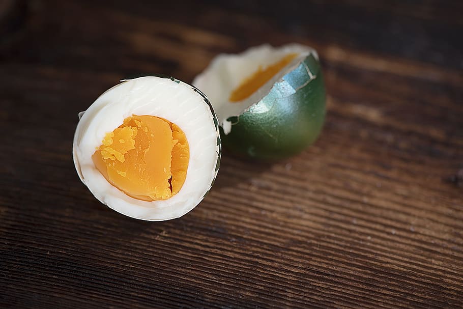 selective focus photography of sliced boiled egg on brown wooden surface