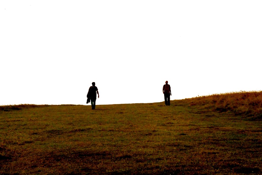 silhouette of two person on hill, person on grass field during day HD wallpaper