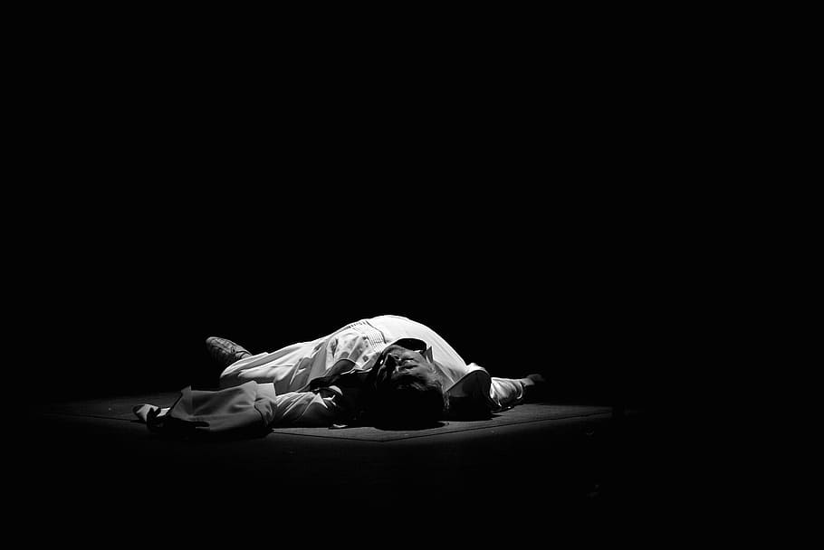 man lying on black surface with spot light, gray, scale, photo