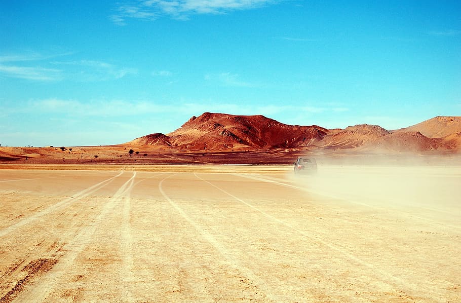 car on a desert overlooking mountain under blue sky, morocco